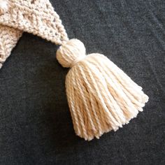 a white knitted hat with tassels laying on top of a black surface