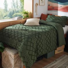 a bed with green bedspread and pillows in a room next to a window