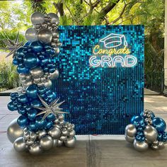 blue and silver balloons are placed in front of a congratulations grad sign on the sidewalk