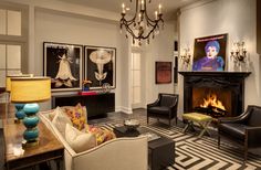 a living room filled with furniture and a fire place under a chandelier in front of a fireplace