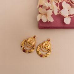 Description: Step into minimal sophistication with our exquisite antique gold-plated Chandbali earrings. Delicately adorned red kempu stones accentuating the Lakshmi temple coin, it exudes timeless allure and sophistication in every detail. Perfect for enhancing any ensemble, these earrings effortlessly harmonize with other antique jewelry for a refined and coordinated look. Details & Specification: Materials used: Brass Alloy with Antique Gold Plating Weight - 10.2 gm Length - 3.5 cm Make it cu Plain Gold Earrings Indian, Lakshmi Design Gold Earrings, Earrings For Daily Wear Gold, Antique Gold Jhumka, One Stone Earrings Gold, Kasu Earrings Gold, Chandbali Earrings Gold Antiques, Gold Earing Design New, Trending Gold Earrings