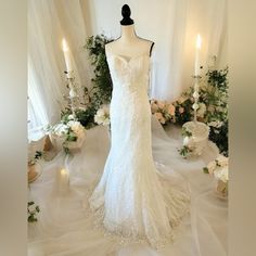 a wedding dress is displayed on a mannequin in front of flowers and candles