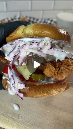 a chicken sandwich with coleslaw and pickles on it