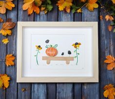 an orange pumpkin sitting on top of a wooden table next to autumn leaves and flowers