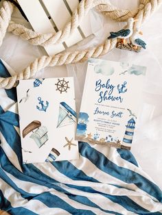 two baby shower items are laying on a bed with blue and white striped sheets next to it