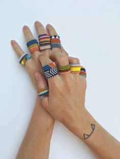 two hands holding different colored rings on top of each other with one hand in the air