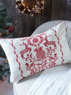 a red and white pillow sitting on top of a chair next to a christmas tree