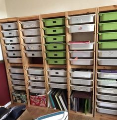 a room filled with lots of storage bins next to a wall full of books