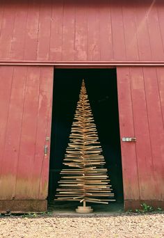 a wooden christmas tree in front of a red barn