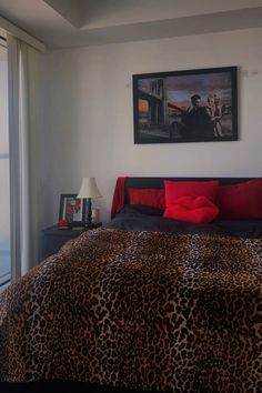 a bedroom with a leopard print comforter and red pillows