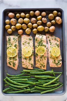 salmon, potatoes and asparagus on a baking sheet with lemons for garnish