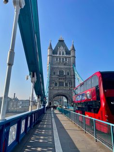 a red double decker bus driving across a bridge