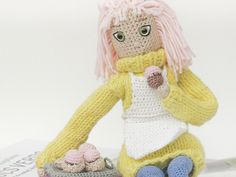 a crocheted doll sitting on top of a table next to a bowl of food