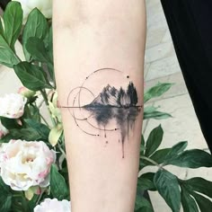 a person's arm with a tattoo on it that has trees and mountains in the water