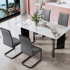 a marble dining table with grey chairs in a pink and white living room next to a large window