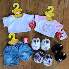 baby clothes and shoes are laid out on the floor next to each other, including two t - shirts