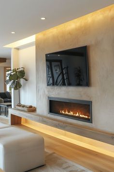 a living room with a television mounted on the wall and a fire place in front of it