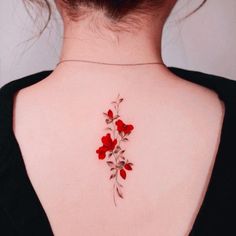 the back of a woman's neck with red flowers on it