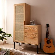 a wooden cabinet sitting next to a guitar on top of a rug in a living room