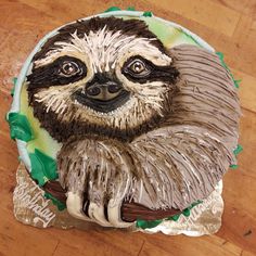 a cake decorated with a sloth on top of a wooden table