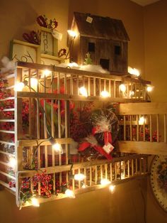 a wooden shelf filled with lots of christmas decorations and lights next to a birdhouse