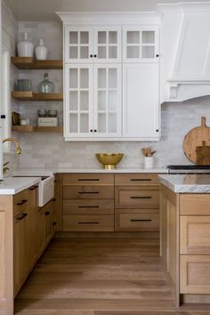 a kitchen with white cabinets and wood floors in the center is featured on this video