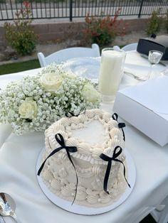 a white cake sitting on top of a table next to a vase filled with flowers