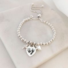 Our sterling silver memorial bracelet is at the heart of our special jewellery collection designed to commemorate cherished memories. Our beautiful range of hand and foot print keepsakes make a gorgeous way to keep a loved one's memory close to heart. All it takes is one of our Magic Inkless Print Kits and a photo of your prints for our engraving team to work from. This elegant sterling silver bracelet combines a silver heart charm which can be engraved with your loved one's hand or foot print, Silver Engraved Bracelet For Memorial, Silver Engraved Bracelet For Memorials, Engraved Silver Bracelet For Memorial, Memorial Engraved Silver Bracelets, Silver Bracelets Keepsake For Mother's Day, Sterling Silver Keepsake Bracelet, Sterling Silver Keepsake Bracelets In Silver, Carton Texture, Engraved Handwriting