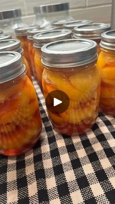 several jars filled with pickles sitting on top of a checkered table cloth