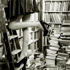 a woman standing on a ladder in front of a bookshelf full of books