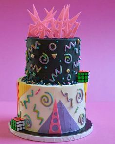 a three tiered cake with colorful decorations on it's sides and pink background