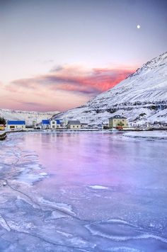 an icy lake with houses and mountains in the background