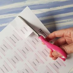 a person holding a pink pair of scissors in their left hand, next to a piece of paper with the word print on it