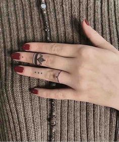 two fingers with tattoos on them are next to a beaded bracelet and ring necklace