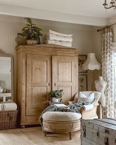 a living room filled with furniture next to a tall wooden armoire and a window