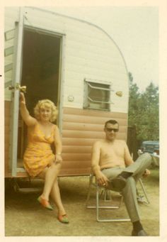 a man and woman sitting in front of a trailer