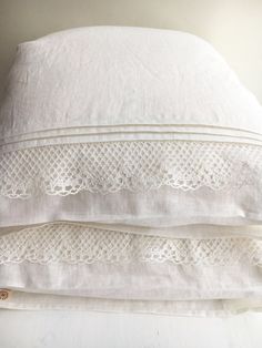 three white pillows stacked on top of each other with lace trimming around the edges