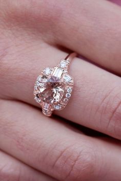 a close up of a person's hand wearing a ring with an oval shaped morganite