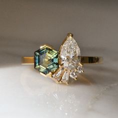 an engagement ring with two pear shaped cut diamonds on the front and side, set in yellow gold