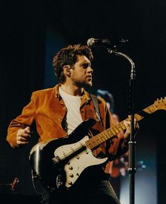 a man playing an electric guitar in front of a microphone