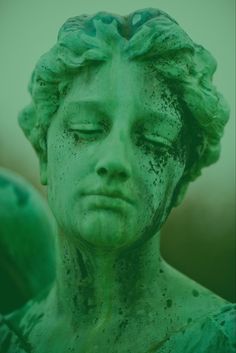 a green statue with its eyes closed