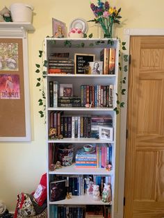 a bookshelf filled with lots of books next to a wooden door in a room