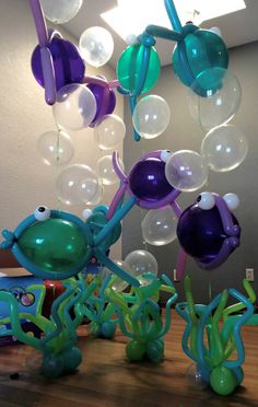 some balloons are floating in the air on top of a wooden table with an octopus