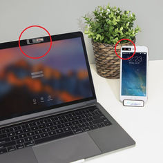 an open laptop computer sitting on top of a white desk next to a cell phone