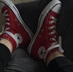 someone is wearing red converse shoes while sitting on a couch