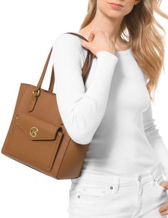 Styled with a chic front pocket detail and gleaming logo hardware for added modern interest, this leather tote is streamlined for on-the-go looks.Medium sized bag; 13"W x 9-1/2"H x 5-1/4"D (width is measured across the bottom of handbag)9"L handlesZip closureGold-tone exterior hardware, 1 snap pocket & logoInterior: 1 back zip pocket, 2 back slip pockets, 6 front slip pocketsLeather; lining: polyesterColor: Luggage Tea Rose, Pocket Detail, Leather Tote, Front Pocket, Zip Pockets, Michael Kors, Exterior, Tea, Leather