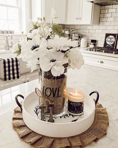 a vase filled with white flowers sitting on top of a table next to a candle