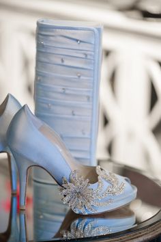 a pair of blue high heel shoes sitting on top of a table next to a vase