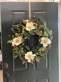 a green door with a wreath on it and flowers hanging from the front doors handle