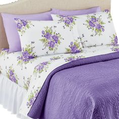 a bed with purple flowers and white sheets